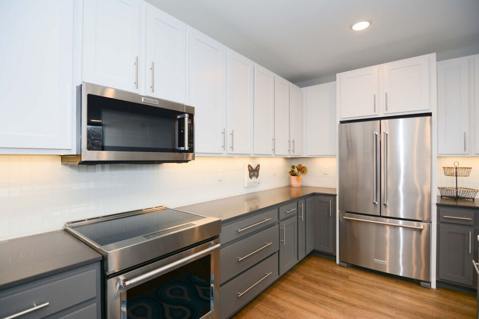 Kitchen with stainless steel appliances and gray and white cabinets.