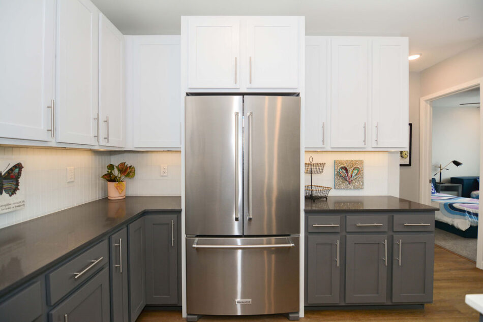Stainless steel fridge surrounded by cabinets.