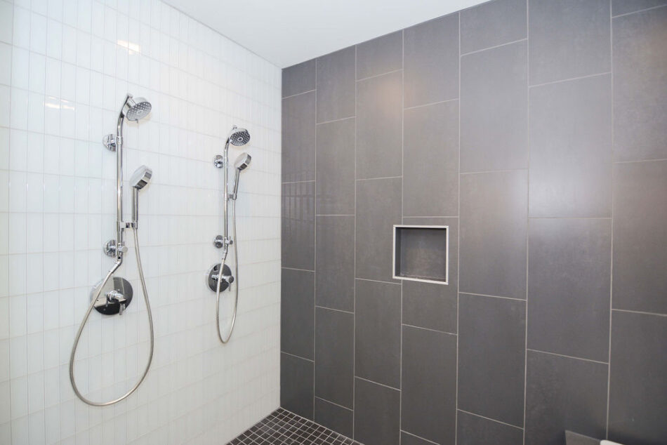 Two-person shower with gray tile.