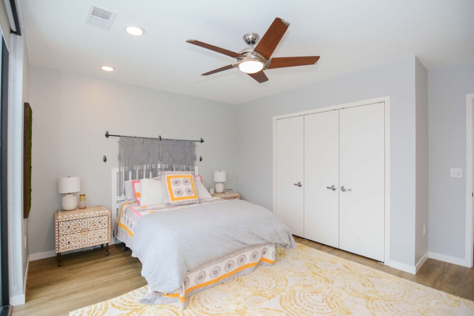 Bedroom with white closet doors and ceiling fan.