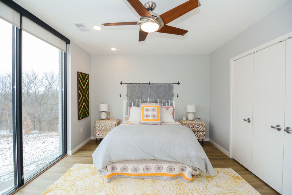 Bedroom with huge windows and three closet doors.