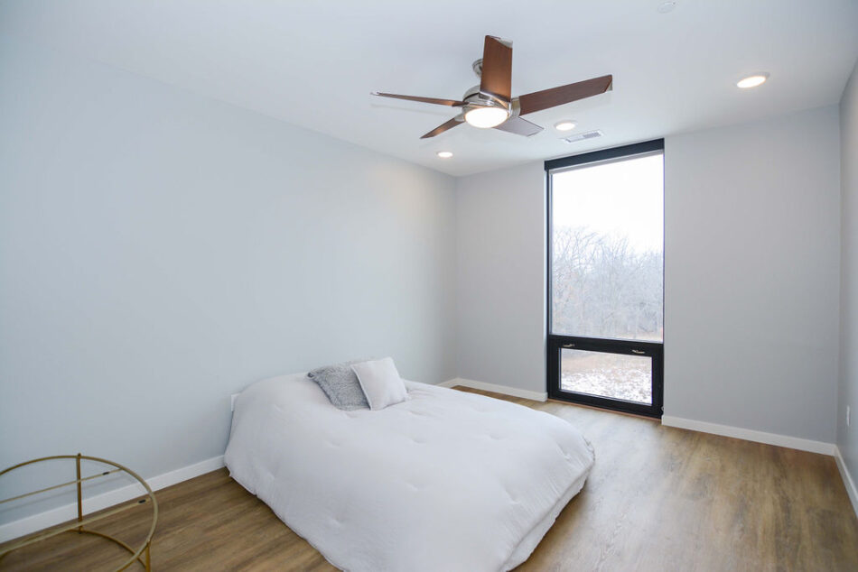 Bedroom with floor-to-ceiling window and ceiling fan.