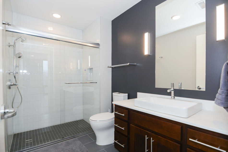 Bathroom with brown cabinets and glass shower enclosure.
