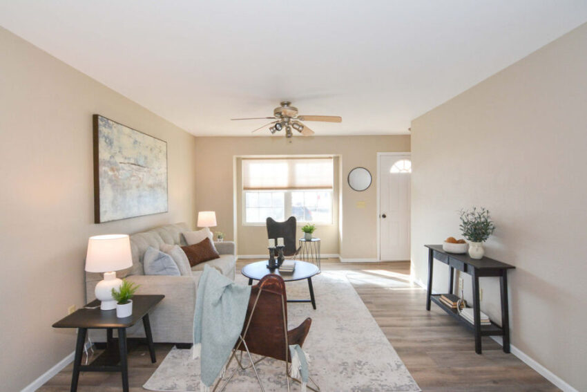 Living room with LVP flooring and large windows beside front door.
