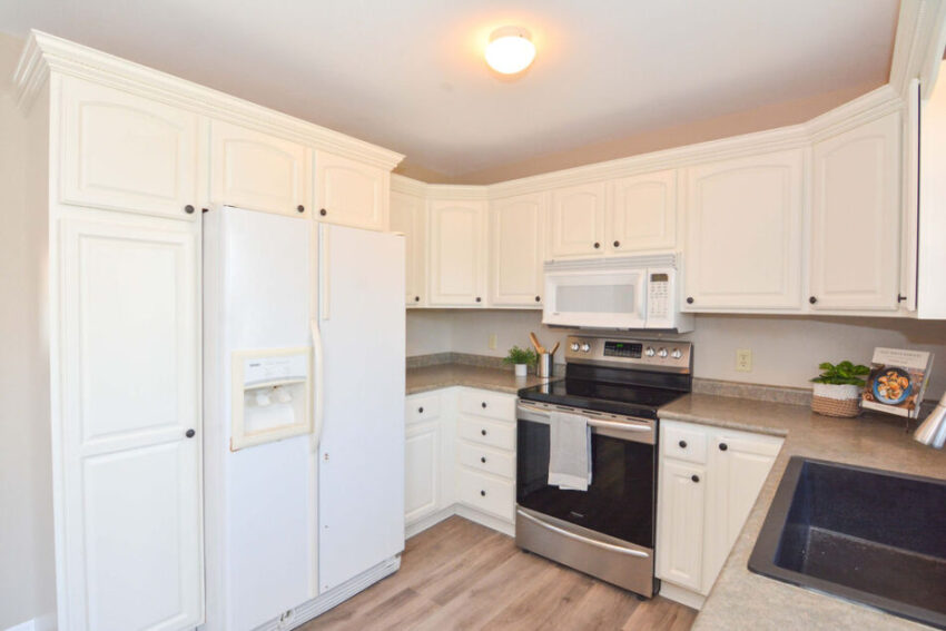 Kitchen with white fridge surrounded by cabinets.