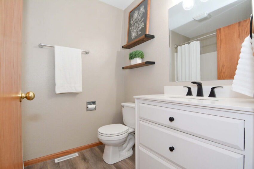 Bathroom with white vanity, black faucet, and large mirror.