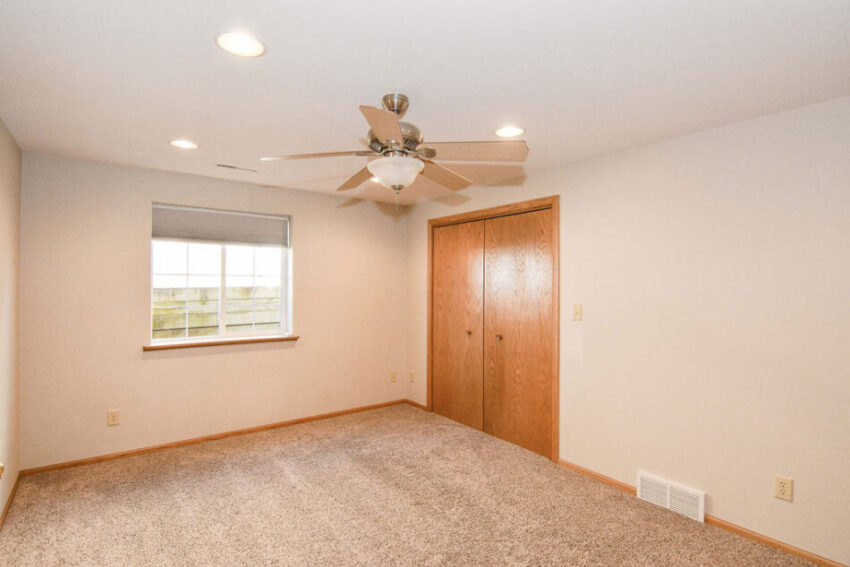 Bedroom with ceiling fan and beige carpet.