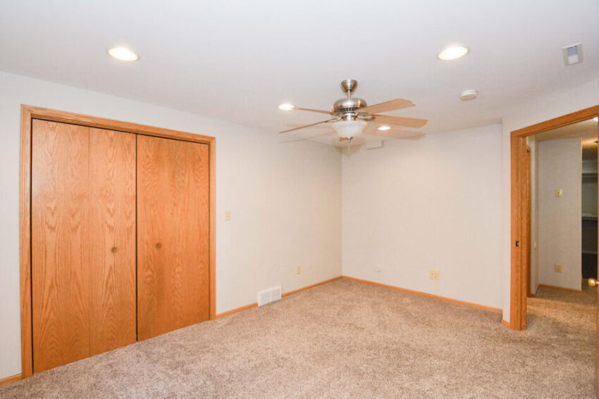 Bedroom with ceiling fan and sliding closet doors.