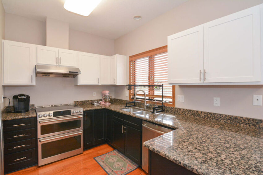 Kitchen with granite counter-tops, window behind sink, and oven with hood.