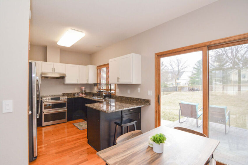 Dining room with kitchen view and stoop visible through double doors.
