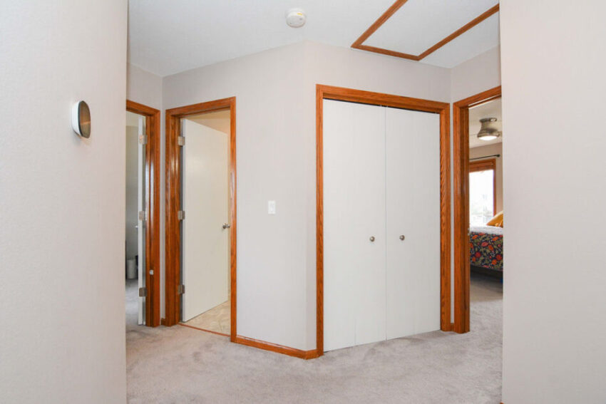 Hallway with storage closet and bedoorm doors.