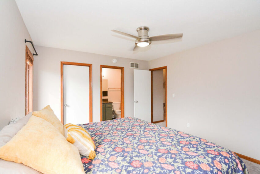 Carpeted bedroom with ceiling fan and attached bath.