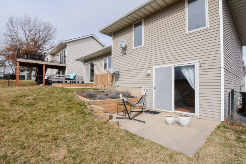 Back of house with stoop beyond basement walk-out doors, firepit, and deck near kitchen exit.