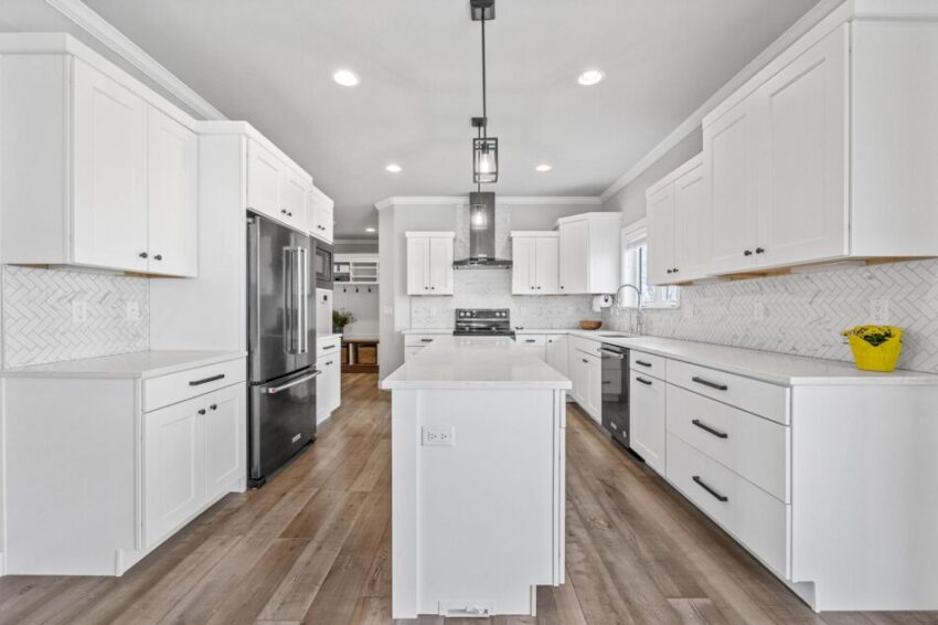 Large kitchen with white cabinets and white tile backsplash.