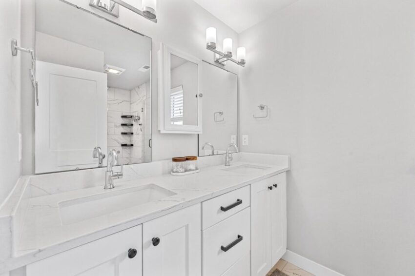 Bathroom with double sinks, gleaming counter, and white cabinets.