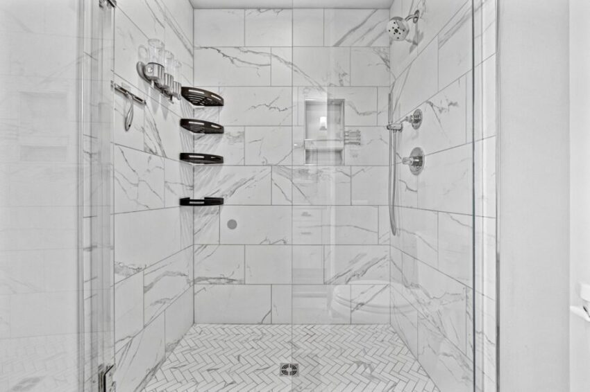 Tile shower with glass door and silver fixtures.