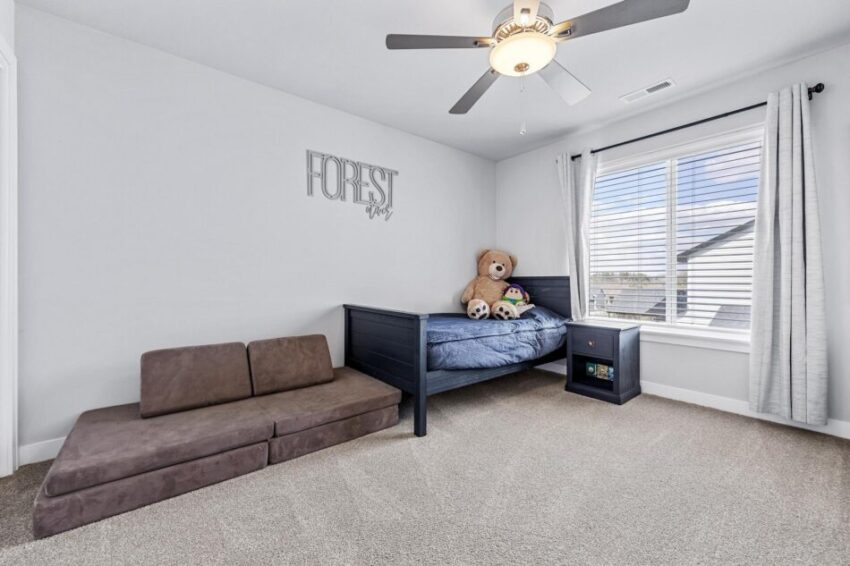 Bedroom with beige carpet and ceiling fan.