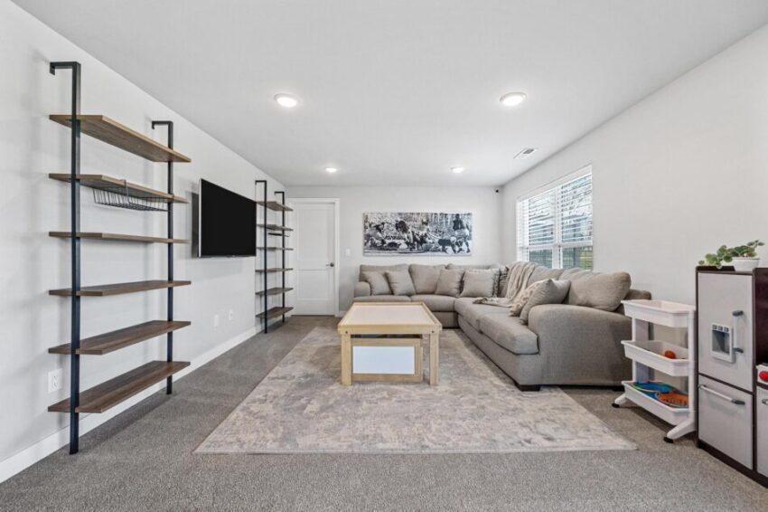 Basement den with pipe shelves and mounted television.