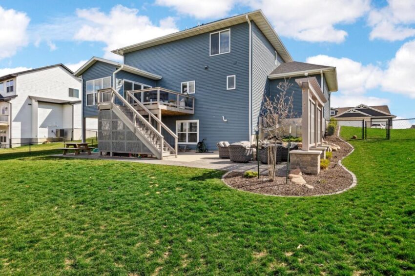 Back view of two-story house with blue siding and landscaping.