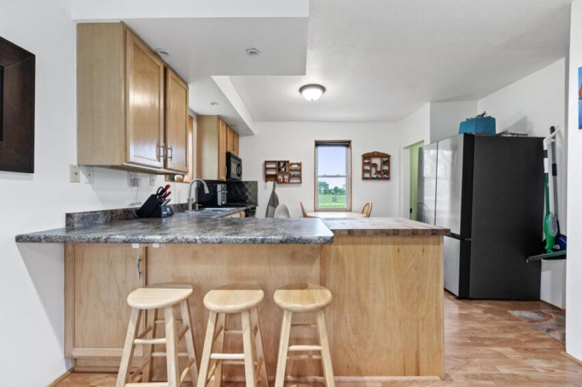 Three stools at counter with overhang in kitchen.
