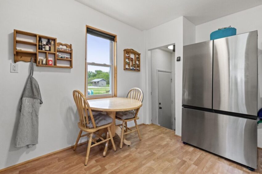 Kitchen table beside window and stainless steel fridge.