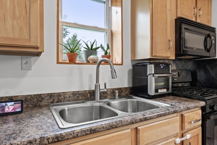 Stainless steel kitchen sink with shining faucet and gray counter.