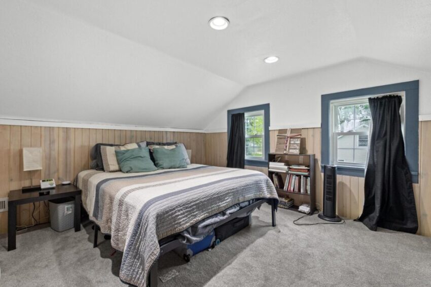 Bedroom with gray carpet and dark curtains.