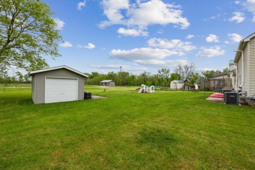 Back yard with green lawn and beige shed.