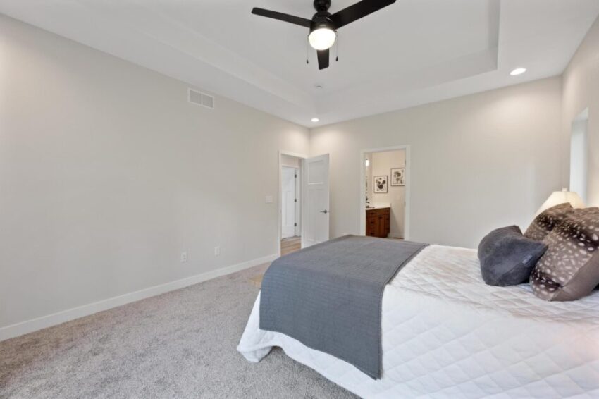 Bedroom with white walls and ceiling fan.