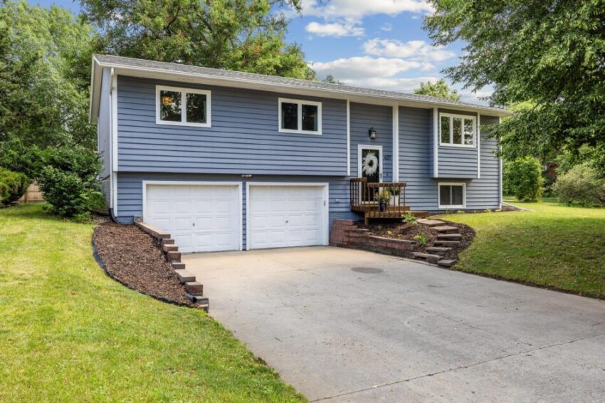 Charming blue home with driveway and garage.