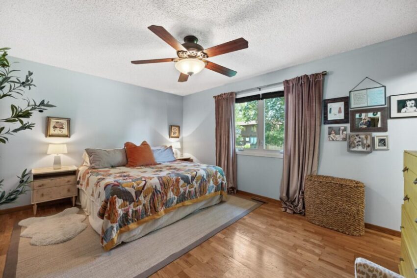 Bedroom with ceiling fan and large windows.