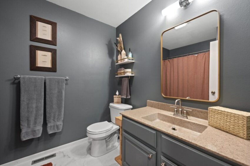 Bathroom with gray walls and corner shelves.