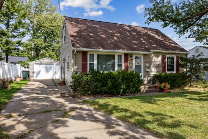 House with concrete driveway leading to one-car garage and back.