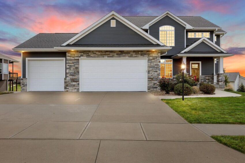 Home with glowing windows and concrete driveway.