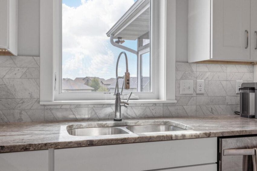 Kitchen with modern faucet, stainless steel sink, and window.