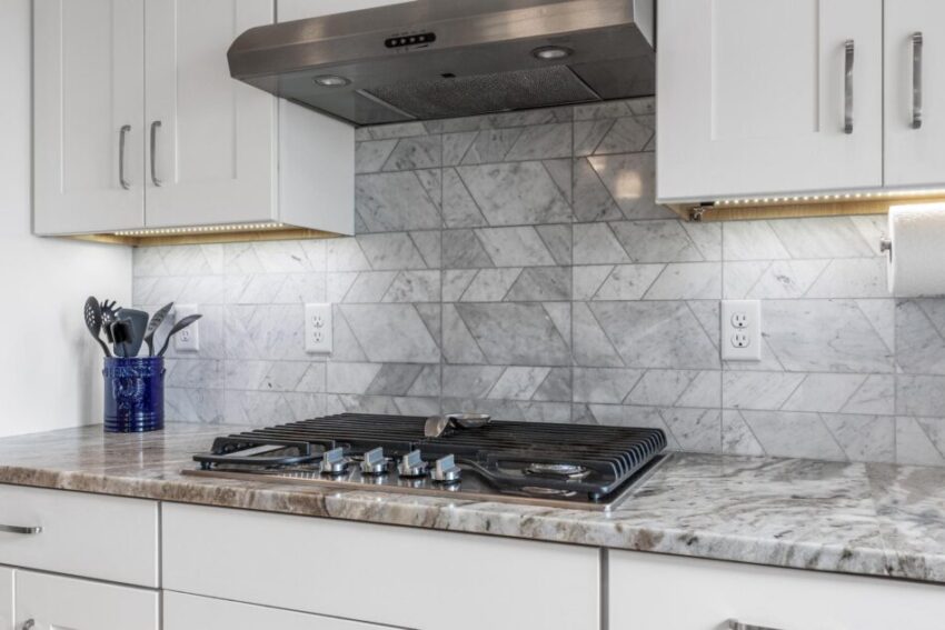 Range with marble countertop and gray backsplash.