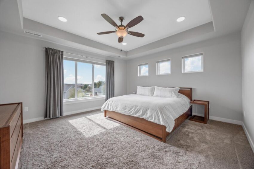 Bedroom 1, with light walls, beige carpet, and ceiling fan.