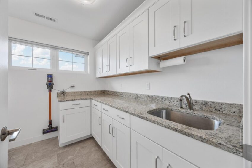 Laundry room with large countertop, sink, and white cabinets.