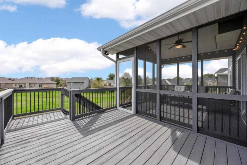 Deck beyond screened in porch with stairs leading down to yard.