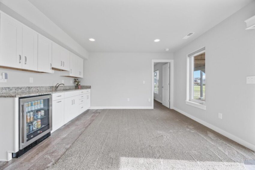 Lower level kitchen area with sink, countertops, and white cabinetry.