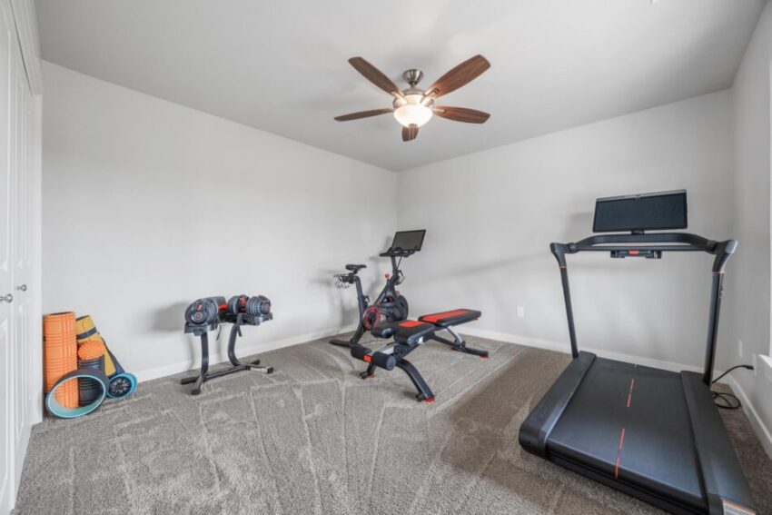 Lower level workout area with ceiling fan and light walls.