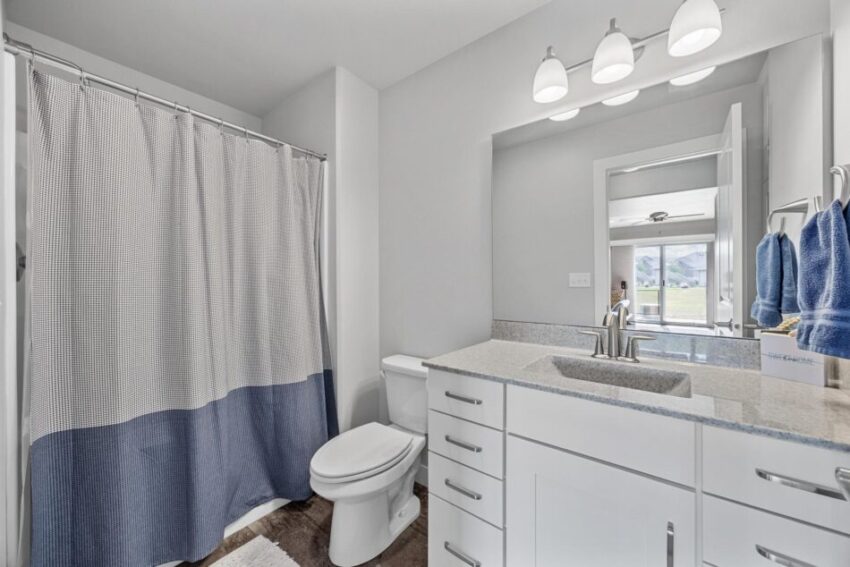 Bathroom 4, with shower curtain, white cabinets, and gray countertop.