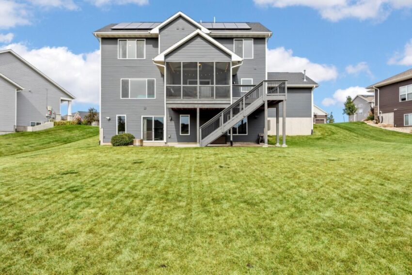 Back of home with screened in porch, deck, and basement exit.