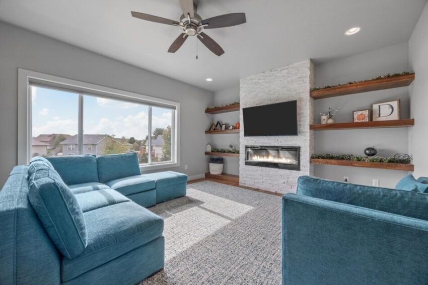 Living room with stone fireplace and built in wooden shelves.