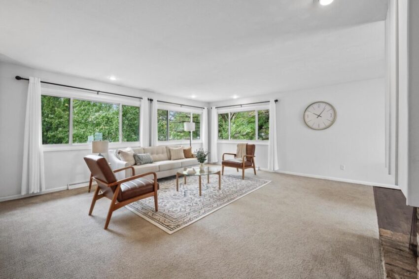 Light-filled living room with large windows overlooking trees.
