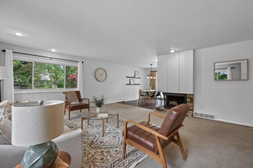 Spacious living room with fireplace, beige carpet, and light gray walls.