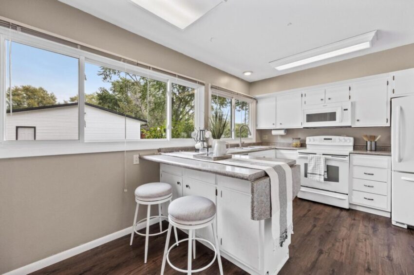 Kitchen with vinyl floor, gray countertops, white cabinets, and beige walls.