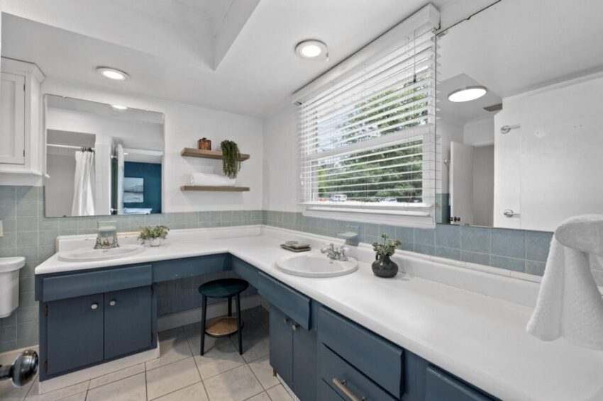 Bathroom with navy-blue cabinets, lighter blue tile walls, and tile floor.