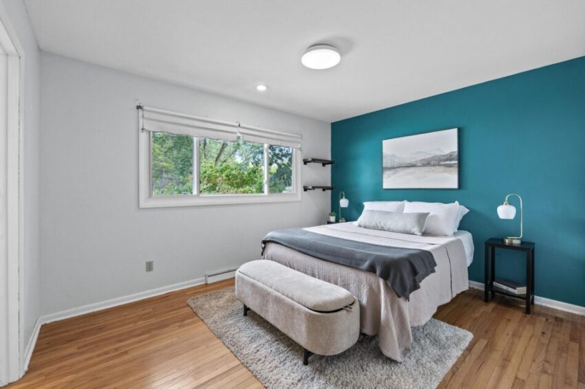 Bedroom 1, with wood floors, ceiling light, and bright blue accent wall.