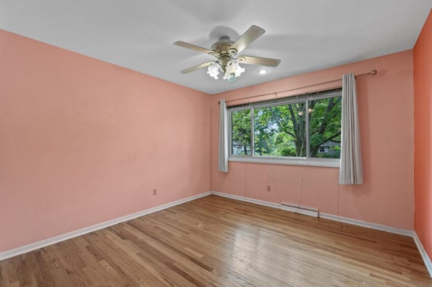 Bedroom 2, with pink walls, wood floor, and ceiling fan.